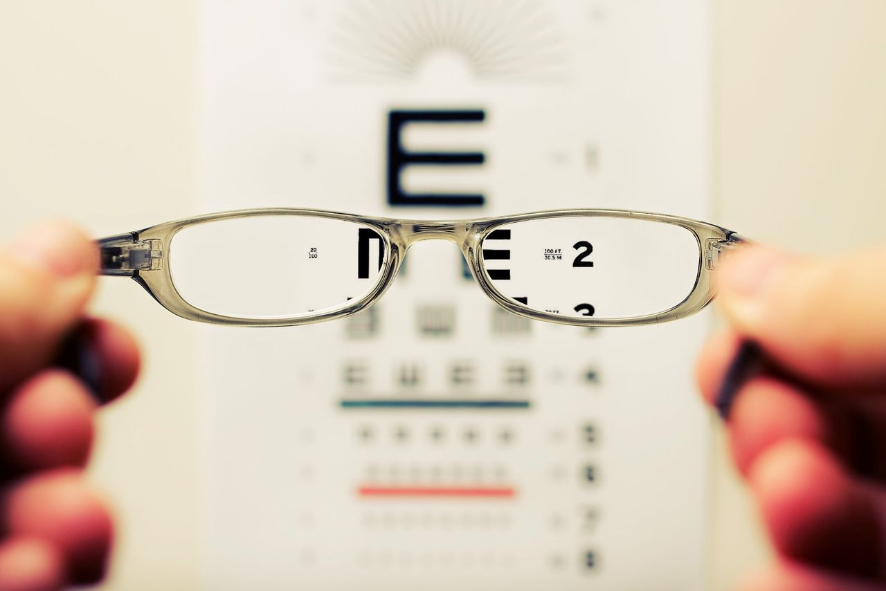 Glasses held up in front of an eye test chart
